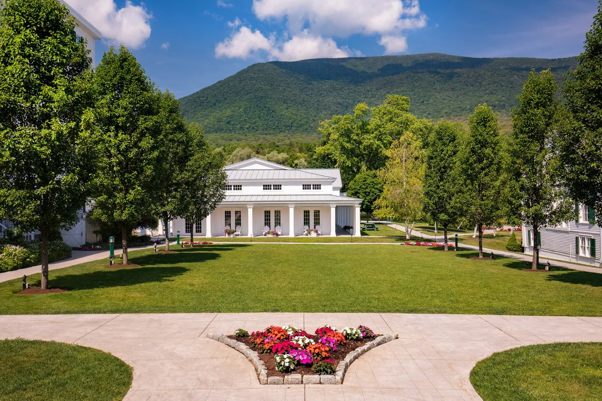 This image features the resort’s elegant main building set against a majestic mountain backdrop, with a vibrant flower bed and perfectly manicured lawn in the foreground. The spacious grounds suggest ample room for gatherings, outdoor games, and leisurely walks, while also emphasizing the natural beauty surrounding the property.