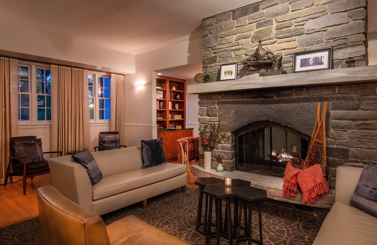 A warmly lit interior space centered around a rustic stone fireplace, surrounded by soft, comfortable seating and accented by candlelight. The setting feels intimate and peaceful, ideal for unwinding after a day of adventure or enjoying a quiet, private retreat.